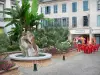 Tarbes - Place agrémentée d'une fontaine, de fleurs et d'arbustes, terrasse de café et façades de maisons