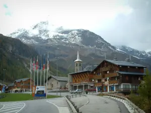 Tignes - Chalets and church of the ski resort (winter sports), lined flags and mountain with snowy summit (peripheral zone of the Vanoise national park)