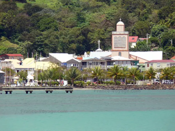 La Trinité - Clocher de l'église de la Sainte-Trinité, palmiers et maisons du bourg au bord de l'océan Atlantique