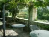 Tuinen van de priorij Notre-Dame d'Orsan - Tafels en stoelen onder een pergola, tuin en bomen op de achtergrond