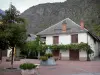 Valbonnais - Village Entraigues: plein met een fontein, bomen en bloemen, dorpshuizen en de bergen op de achtergrond