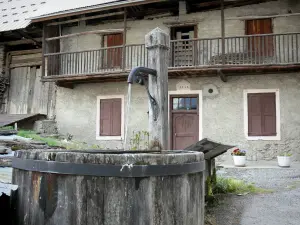 Vallouise - Wooden fountain and house of the village; in the Écrins National Nature Park