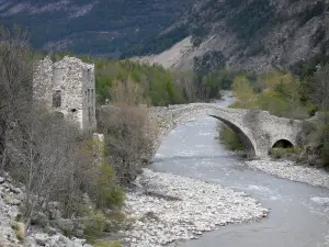 Verdon upper valley - Old stone bridge spanning the River Verdon, ruin of a house and trees along the water
