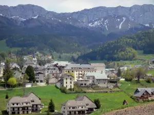 Villard-de-Lans - Espadaña de la iglesia de San Bonet, casas y edificios de la aldea (estación de esquí, esquí de invierno y verano Resort), prados, bosques y montañas en el fondo, en el Parque Natural Regional de Vercors (sólido Vercors)