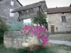 Villeneuve d'Aveyron - Flower-bedecked well and facades of houses in the fortified town