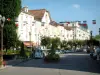 Vittel - La calle de la ciudad (estación) con las banderas que cuelgan de spa, tren turístico, los árboles y los edificios