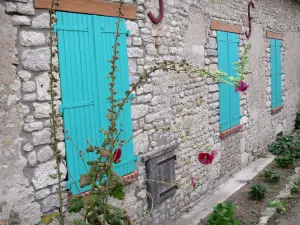 Yèvre-le-Châtel - Maison en pierre aux volets de couleur bleu turquoise et roses trémières