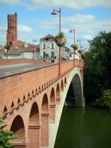 Вильнёв-сюр-Ло - Освободительный мост (Pont Neuf), украшенный фонарными столбами и цветами, река Лот, колокольня Екатерининской церкви и дома в старом городе