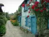 Жерберуа - Голубой дом и его взбирающийся куст роз (красные розы), мощеный переулок с цветами и растениями