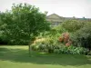 Компьен - Парк (сад) замка с газоном, деревом, растениями, цветами и кустарниками, фасад замка на заднем плане