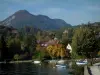 Таллуары - Озеро, гавань с лодками, дома и колокольня деревенской церкви, деревья в цветах осени, леса и горы