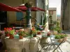 蒙斯 - 喷泉装饰着花盆，椅子和桌子在前景，咖啡馆露台和村庄的房子