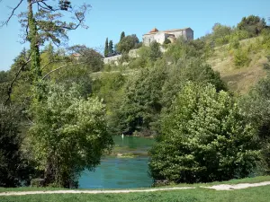 Abrir - Igreja Sainte-Madeleine estilo românico com vista para as fontes do Touvre (ressurgimento), árvores à beira da água