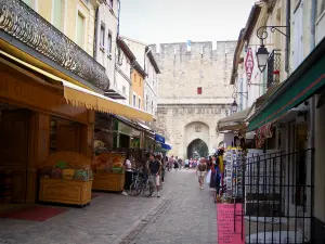 Aigues-Mortes - Rue bordée de magasins et de maisons, porte de la Gardette en arrière-plan