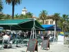 Ajaccio - Terrasse de restaurant animée avec palmier et hôtel de ville (mairie) en arrière-plan