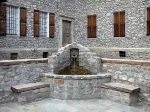 Allos - Brunnen, Sitzbank und Haus aus Stein