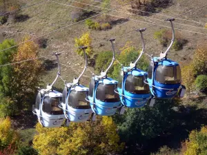 Alpe d'Huez - Teleférico (ski lift) do inverno e verão sports resort (resort de esqui), árvores abaixo nas cores do outono