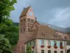 The Alsace Wine Route - Gueberschwihr: House decorated with geranium flowers, trees and church of the village