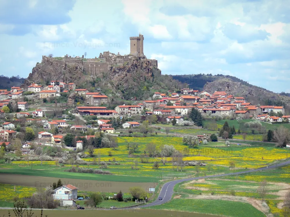 Guida dell'Alta Loira - Paesaggi dell'Alta Loira - Strada fiancheggiata da prati fioriti, con vista sul castello di Polignac arroccato sulla sua collina di basalto e le case del borgo medievale sotto la fortezza