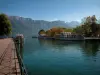 Annecy lake - In Annecy: quai Napoleon III (quayside), jetty (port) with moored boats, trees with autumn colours, lake and mountains in background