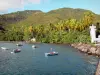 Anse a la Barque - Farol na Enseada à la Barque, árvores e coqueiros ao longo do mar, e barcos flutuando na água; à beira das comunas de Vieux-Habitants e Bouillante, na ilha de Basse-Terre