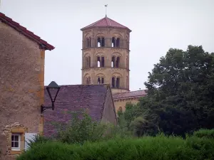 Anzy-le-Duc - Octagonal bell tower of the Notre-Dame-de-l'Assomption church of Romanesque style, houses of the village and trees; in Brionnais