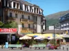 Ax-les-Thermes - Station thermale : façades d'immeubles, terrasse de restaurant ombragée de parasols, bancs et fleurs