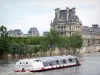 Banks of the Seine river - Cruise ship sailing on the Seine river with a view of the Louvre palace
