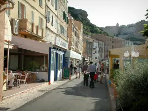 Bonifacio - Street lined with restaurant terraces and cafés (low city), citadel in background