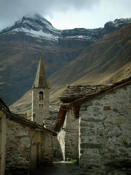 Bonneval-sur-Arc - Las viejas casas de piedra con tejados de pizarra, la torre de la iglesia del pueblo de Saboya y la montaña nevada, en la Haute-Maurienne (Parque Nacional de Vanoise)