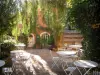 Bormes les Mimosas - Cadeiras e mesas brancas de um café terraço, árvores, salgueiro-chorão e casa de aldeia