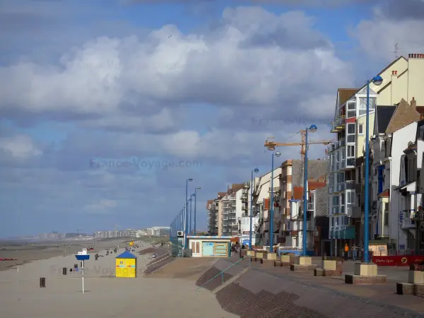 Bray-Dunes - Côte d'Opale : plage de sable, digue-promenade jalonnée de lampadaires, maisons et immeubles de la station balnéaire, nuages dans le ciel bleu