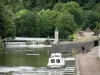 Canal du Nivernais - Bateau de plaisance, canal du Nivernais et son écluse (à droite), buste de Jean Rouvet, rivière Yonne (à gauche), et arbres au bord de l'eau ; à Clamecy