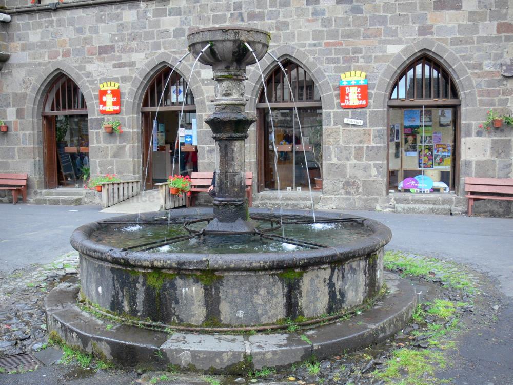 Guide du Cantal - Salers - Fontaine place Tyssandier d'Escous et maison de Vernhes abritant la mairie et l'office de tourisme intercommunal du Pays de Salers