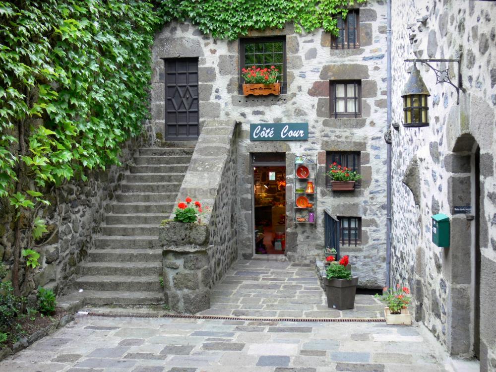 Guide du Cantal - Salers - Maison en pierre décorée de géraniums