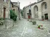 Castelnau-Pegayrols - Rua pavimentada, igreja de Saint-Michel, casas de pedra e decorações florais da vila medieval