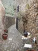 Castelnou - Geplaveide straat met stenen huizen, kleine tafel en stoelen in de voorgrond