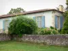 Castelo de Gaujacq - Fachada com venezianas azuis da casa senhorial e suas plantas em flor