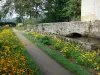 Castelo dos Martinanches - Beco forrado com flores e pequena ponte abrangendo o fosso; no município de Saint-Dier-d'Auvergne; no Parque Natural Regional de Livradois-Forez