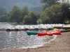 Chambon lake - Beach, canoes, pedal boats and trees lining the water; in the Auvergne Volcanic Regional Nature Park in the Monts Dore mountain area 