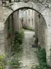 Charroux - Passage voûté, et ruelle pavée et fleurie bordée de maisons en pierre