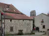 Charroux - Façades de maisons, puits fleuri et clocher tronqué de l'église Saint-Jean-Baptiste