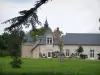 Château de Beauregard - Branches d'un arbre en premier plan, prairie, statue et communs du château