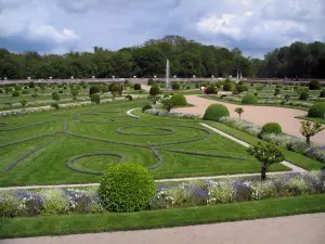 Château de Chenonceau - Diane de Poitiers garden with its formal flowerbeds, its fountain and its shrubs, trees and clouds in the sky