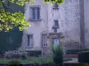 Château des Martinanches - Tour d'escalier et façade du château, jardin fleuri et branches d'un arbre ; sur la commune de Saint-Dier-d'Auvergne