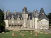 Château du Rocher - Vue sur le château et sa cour d'honneur, pré parsemé de bottes de foin en premier plan ; sur la commune de Mézangers
