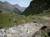 Cirque de Gavarnie - Paysage pendant la montée au pied de la paroi rocheuse du cirque : rochers, pierres, pelouses avec vue sur les montagnes bordant la vallée de Gavarnie
