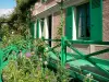 Claude Monet’s house and gardens - Monet's pink house with green shutters and its surroundings with flowers; in Giverny