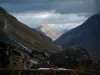 Col du Galibier - Route des Grandes Alpes : amas rocheux, pentes alpines dénudées et montagne au sommet enneigé en arrière-plan