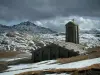 Col de l'Iseran - Parc National de la Vanoise : chapelle Notre-Dame de l'Iseran, pelouses alpines avec de la neige, montagnes enneigées et ciel nuageux (route des Grandes Alpes)